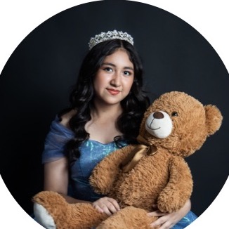 Sofía con vestido azul y un oso de peluche